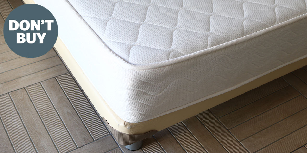 White mattress with a quilted pattern resting on a wooden floor, accompanied by a circular graphic that says "DON'T BUY."