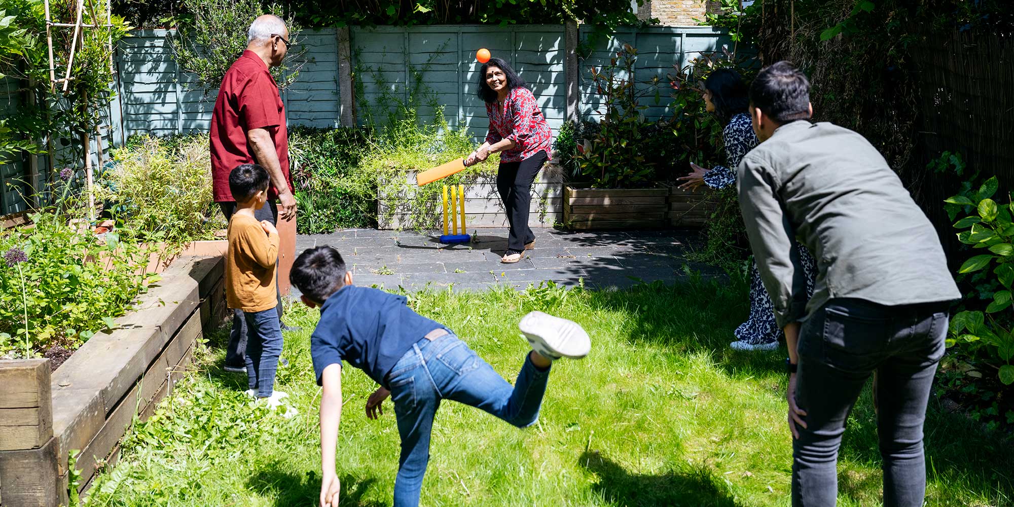 A family playing cricket in their garden