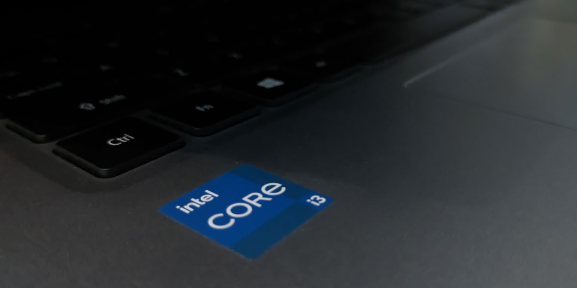 Close-up of a laptop keyboard showing the Intel Core i3 logo on a dark surface. Keys partially visible in the background.