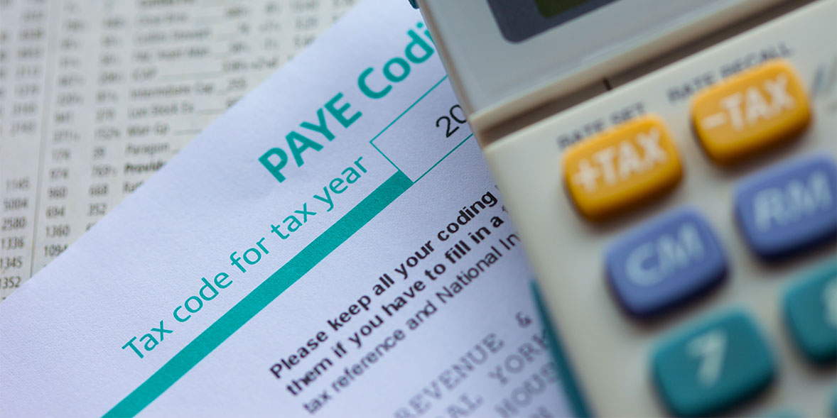 PAYE tax code document with a calculator nearby, highlighting the tax year and instructions for filling details.