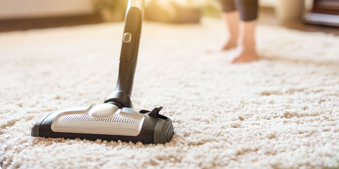 Woman vacuuming a thick carpet