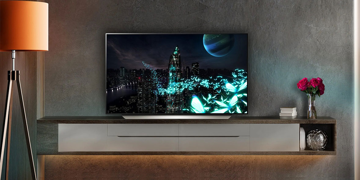 A sleek TV displays a vibrant futuristic cityscape with glowing butterflies and a planet above, on a modern cabinet.