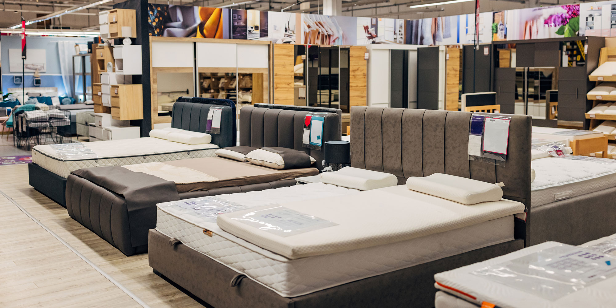 Various beds displayed in a furniture store showroom, featuring modern designs and different mattress styles, neatly arranged