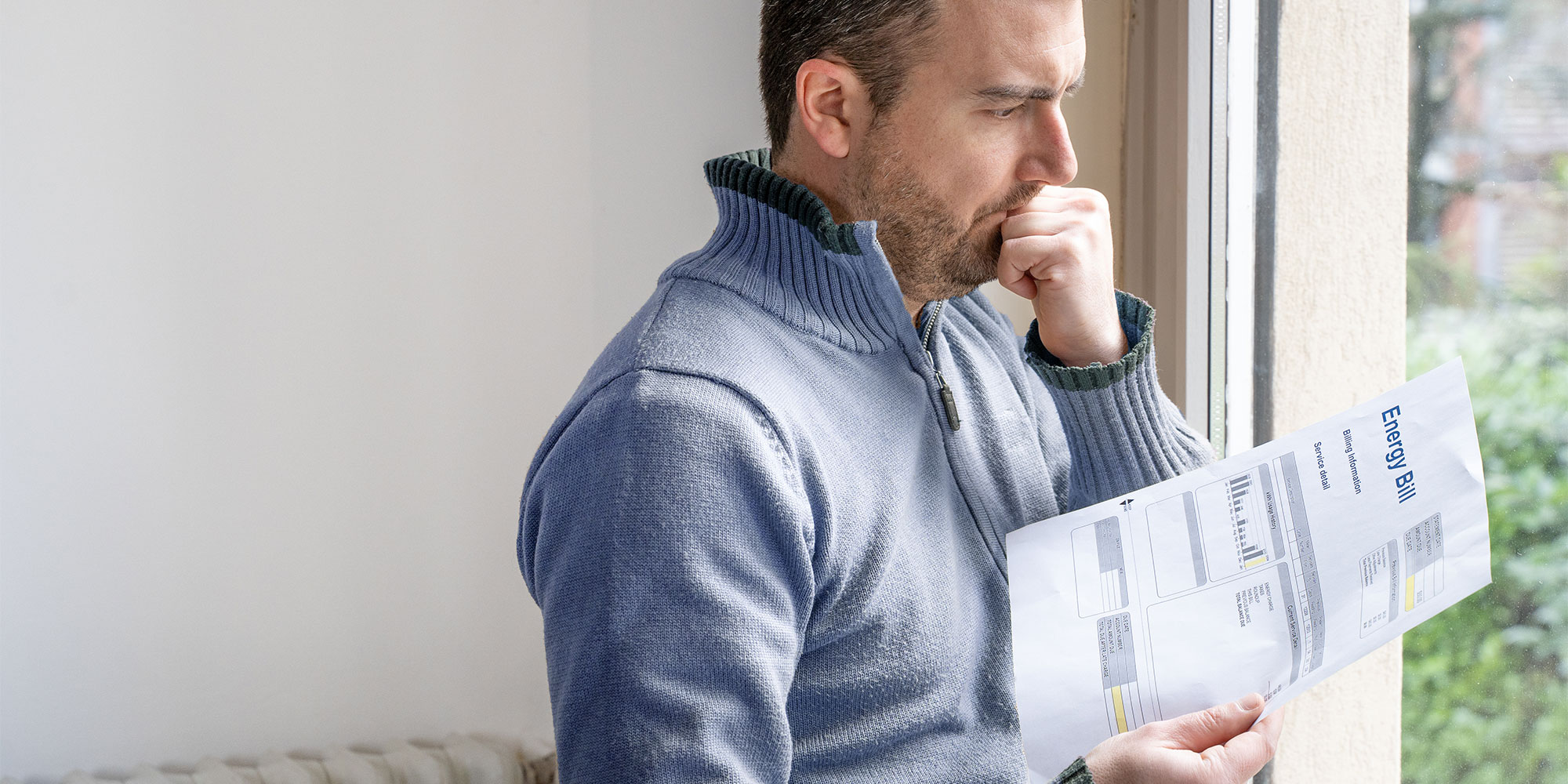 A man standing up with his energy bill in his hand