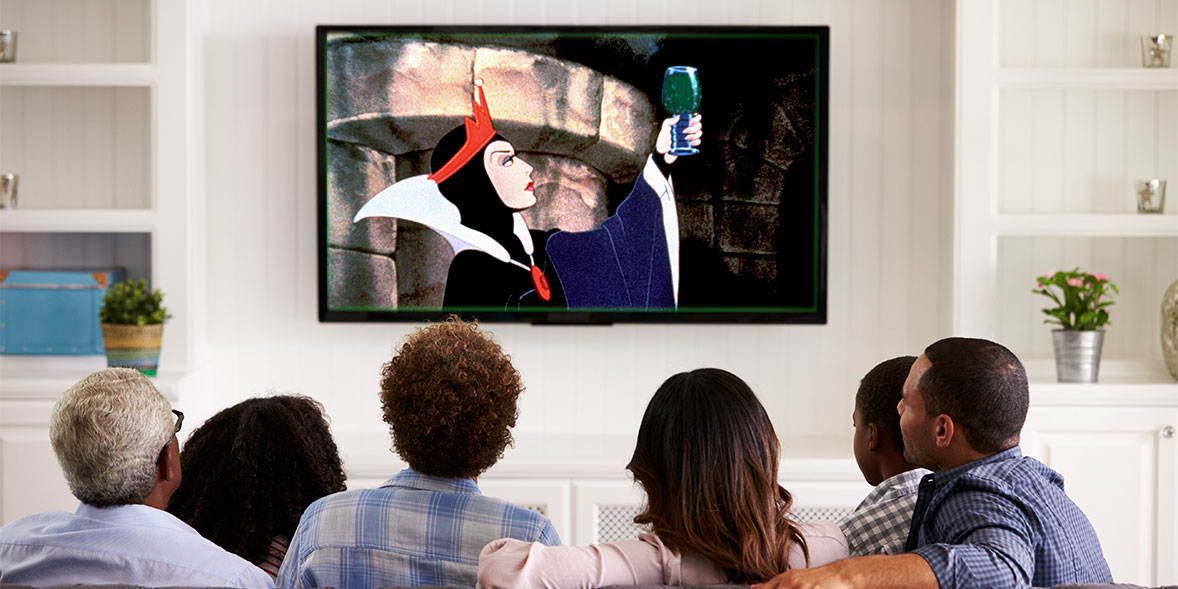 A family watching as Disney villain Maleficent raises a glass of green bubbling liquid