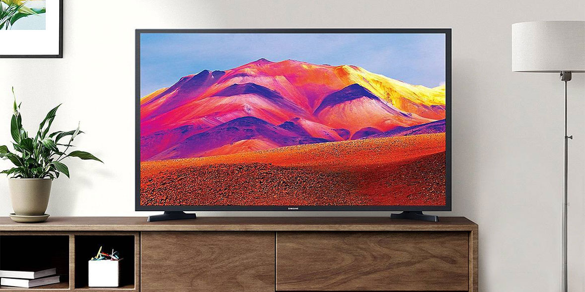 Vibrant landscape on a television screen showcasing colorful mountains and a blue sky, displayed on a wooden console.