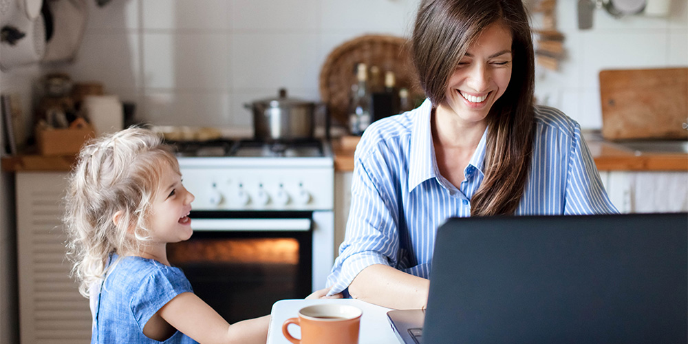 A mother and daughter smile together at a breakfast table