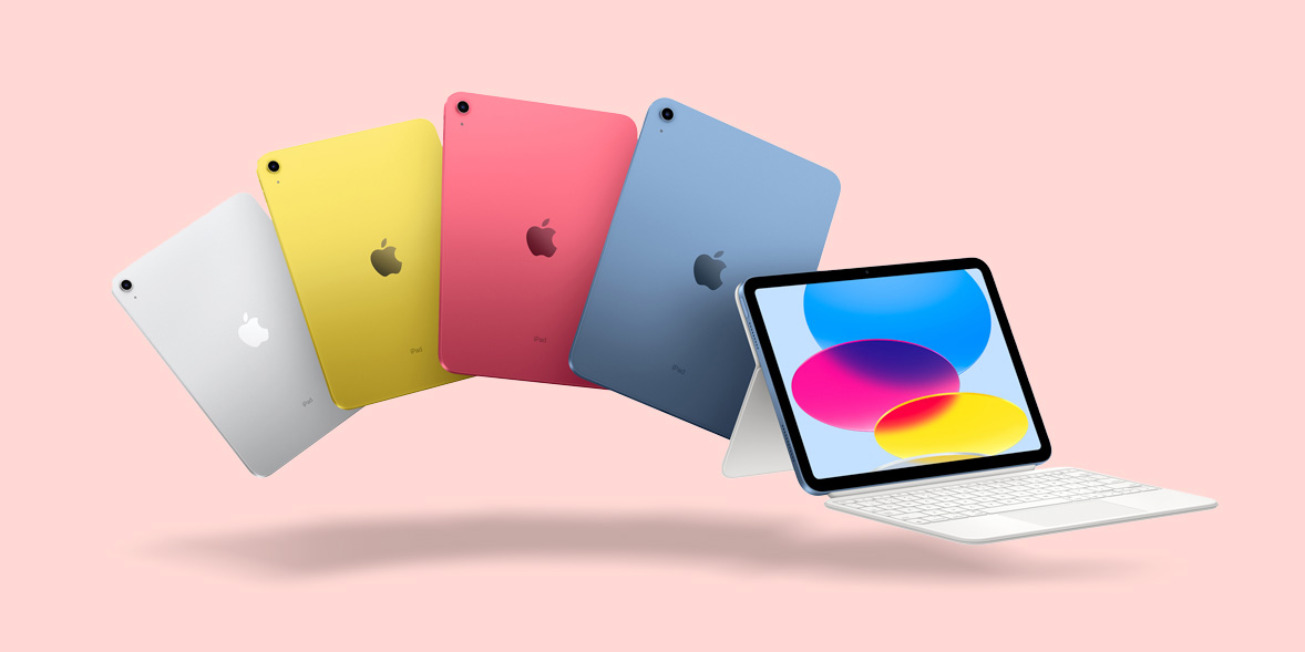 Five colorful iPads in silver, yellow, pink, red, and blue, alongside a white keyboard and a pink background.