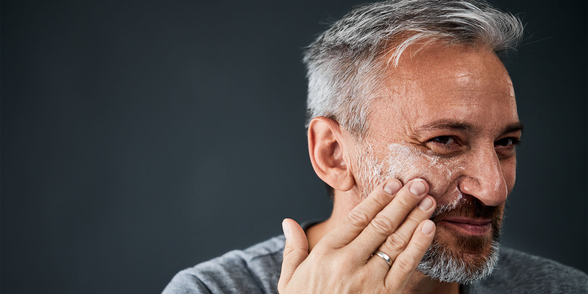 A person putting face cream on their cheek