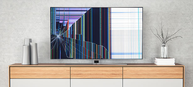 A shattered television screen displays colorful vertical lines and a spiderweb crack, set on a wooden cabinet.
