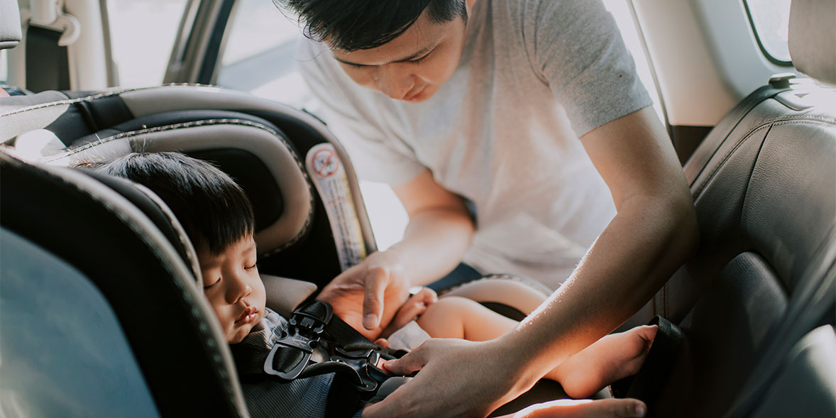 Man putting child into car seat