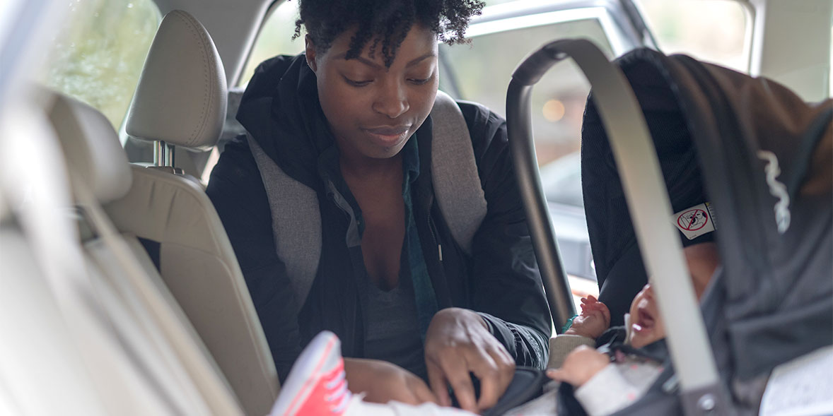 Woman strapping baby into car seat