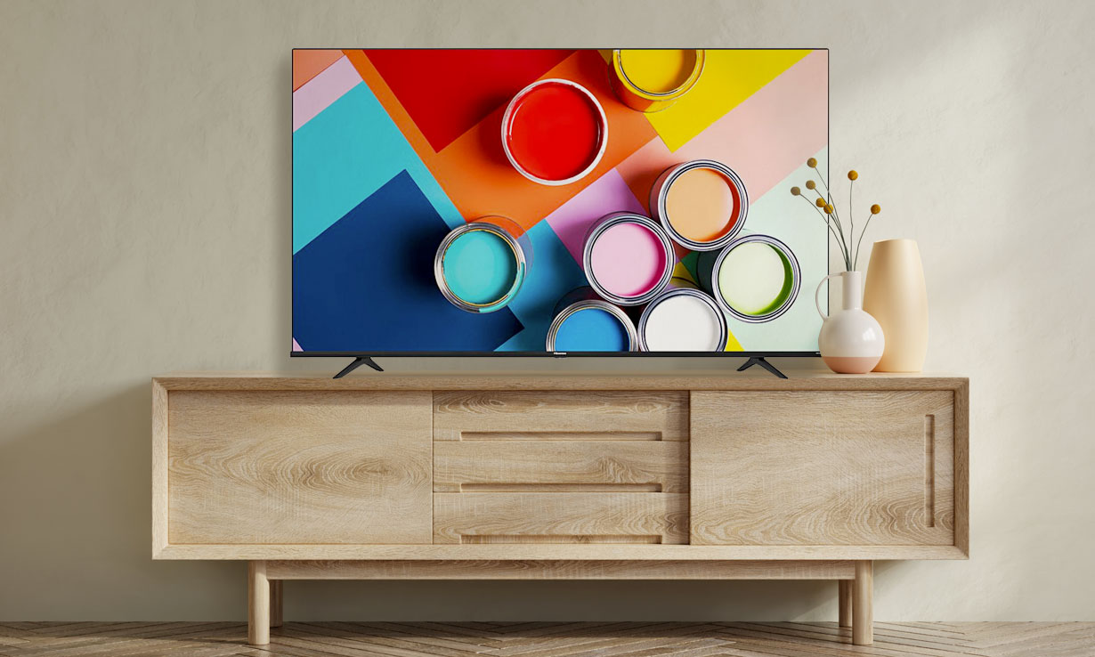 Flat-screen TV showing vibrant paint cans on a colorful background, placed on a wooden cabinet