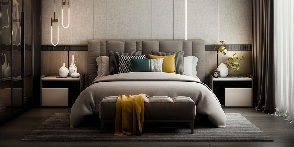 Modern bedroom with a grey upholstered headboard, colorful pillows, a plush bench, and minimalist decor in neutral tones.
