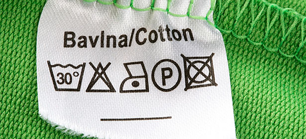 Label with care instructions for a green cotton garment, indicating washing temperature, ironing, and drying symbols.