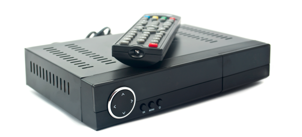Black media player with a circular control button and a remote control resting on top, featuring colorful buttons.